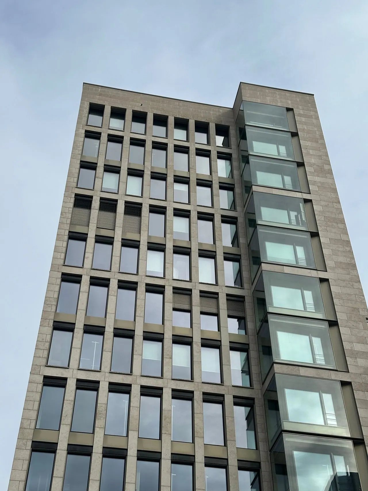 Modern commercial office building facade rising against an overcast sky