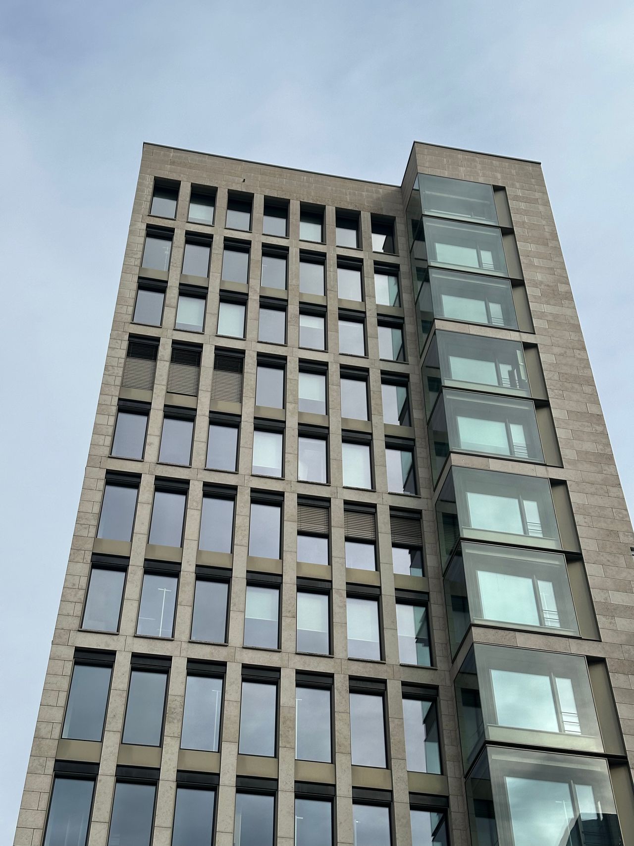 Modern commercial office building facade rising against an overcast sky
